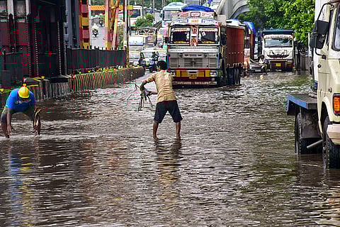 Workers clear a waterlogged road